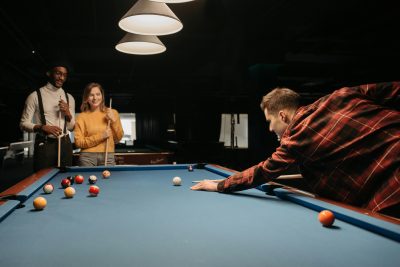A group of friends playing billiards indoors, enjoying leisure time together. Vibrant and relaxed atmosphere. Un groupe d'amis jouant au billard en intérieur, profitant d'un moment de loisir ensemble. Atmosphère dynamique et détendue.