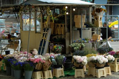 An inviting outdoor flower stall showcasing vibrant bouquets and assorted flowers in a busy market street. Un étal de fleurs extérieur accueillant présentant des bouquets vibrants et des fleurs assorties dans une rue de marché animée.