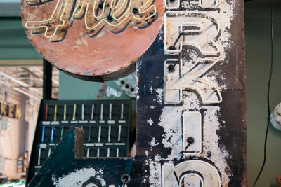 A rustic 'Free Parking' sign with an arrow, inside a Somerville workshop. Un panneau rustique « Free Parking » avec une flèche, à l'intérieur d'un atelier de Somerville.