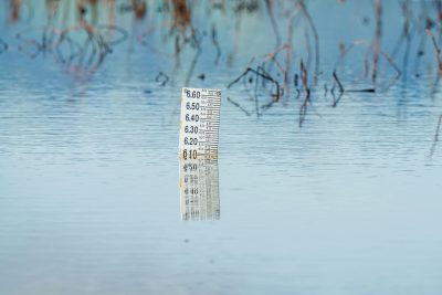 Close-up of a flood gauge in water, reflecting calm surroundings. Perfect for environmental themes. Gros plan d'une jauge de crue dans l'eau, reflétant les calmes environs. Parfait pour les thèmes environnementaux.
