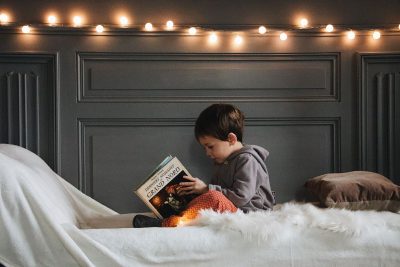 Enfant en train de lire un livre dans sa chambre