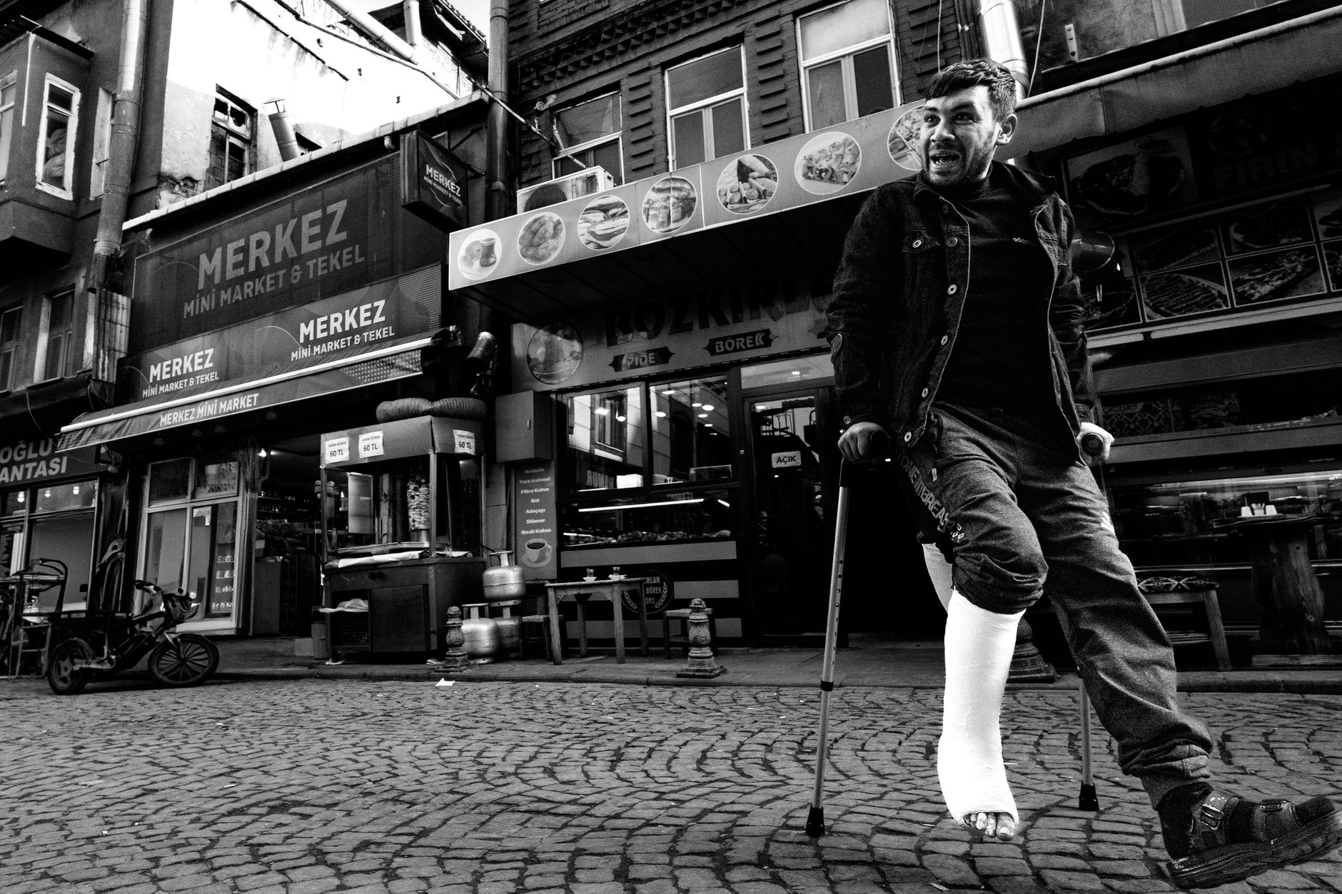 Homme avec une jambe plâtrée se déplaçant en béquilles dans la rue