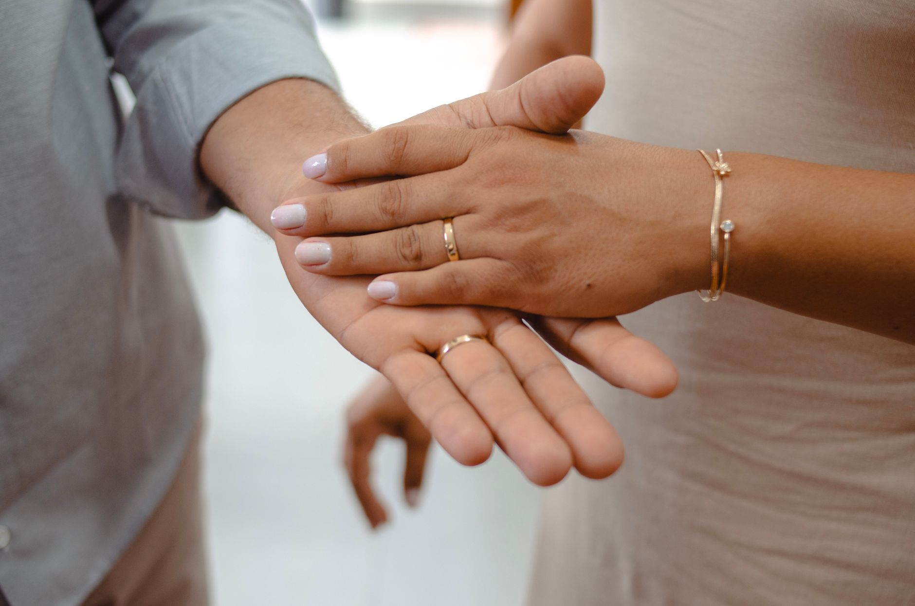 Mains de couple ornées de bagues et bracelets dorés