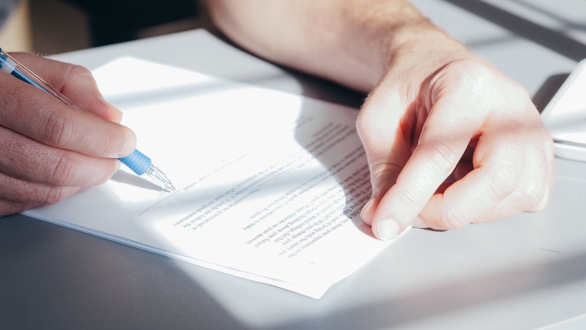 Mains qui signent un contrat au stylo bleu